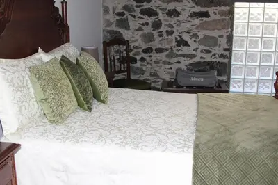 a bedroom with a bed with green and white pillows at A Casa da Carolina in São Vicente