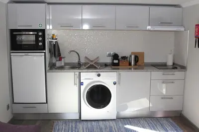 a kitchen with a washing machine and a washer at A Casa da Carolina in São Vicente