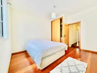 a bedroom with a white bed and a wooden floor at Casa da Minha Luz in Santa Cruz