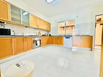 a large kitchen with wooden cabinets and white appliances at Casa da Minha Luz in Santa Cruz