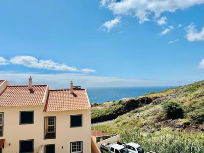 a house with cars parked next to the ocean at Casa da Minha Luz in Santa Cruz