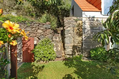 a garden with a stone wall and a wooden door at Romantic Retreat by Slice of Heaven in Jardim do Mar