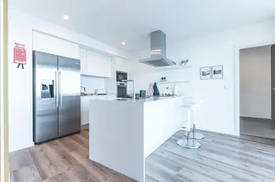 a kitchen with white cabinets and a refrigerator at Xavelha Clifftop by Atlantic Holiday in Câmara de Lobos