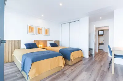 two beds in a white room with a desk and a table at Xavelha Clifftop by Atlantic Holiday in Câmara de Lobos