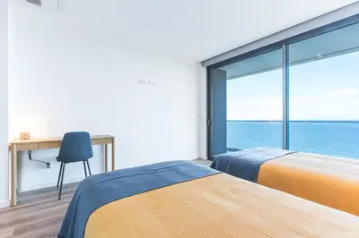 two beds in a bedroom with a view of the ocean at Xavelha Clifftop by Atlantic Holiday in Câmara de Lobos