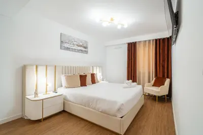 a white bedroom with a bed and a chair at Sunset Luxury Apartment by Amazing Madeira in Câmara de Lobos