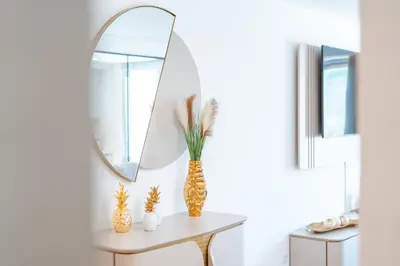 a table with a mirror and a vase on it at Sunset Luxury Apartment by Amazing Madeira in Câmara de Lobos