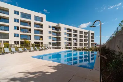 a large white building with a swimming pool and chairs at Sunset Luxury Apartment by Amazing Madeira in Câmara de Lobos