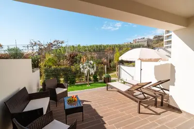 a patio with chairs and an umbrella on a balcony at Sunset Luxury Apartment by Amazing Madeira in Câmara de Lobos