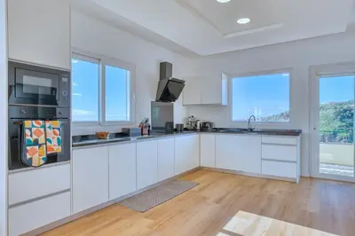 a white kitchen with white cabinets and windows at Skyline Villa by Holiday Rental Madeira in Gaula