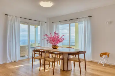 a dining room with a table with a vase of flowers at Skyline Villa by Holiday Rental Madeira in Gaula
