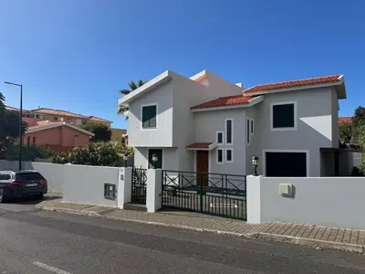 a white house with a fence and a car at Villa Canhas in Canhas