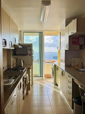 a large kitchen with a view of the ocean at Apartamento Precioso in Arco da Calheta
