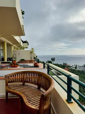 a wooden bench sitting on a balcony overlooking the ocean at Apartamento Precioso in Arco da Calheta