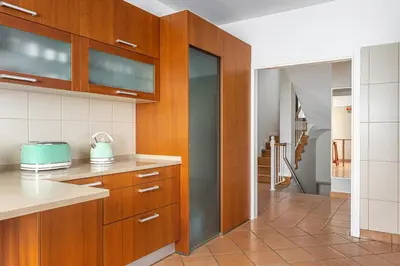 a kitchen with wooden cabinets and a hallway at New Casa Bondi by Your Madeira Rentals in Ponta do Sol