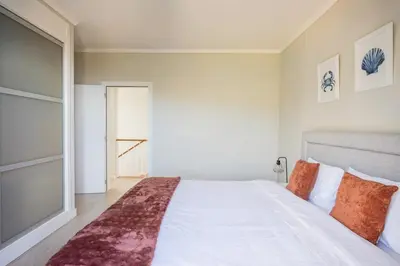 a bedroom with a large white bed with orange pillows at New Casa Bondi by Your Madeira Rentals in Ponta do Sol
