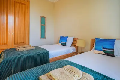 a bedroom with two beds with blue and green sheets at NEW Villa 66 - Palheiro Village by YMR in São Gonçalo