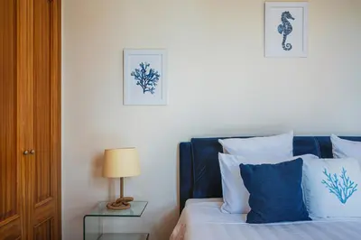 a bedroom with a bed with blue and white pillows at NEW Villa 66 - Palheiro Village by YMR in São Gonçalo