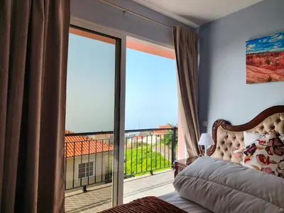 a bedroom with a bed and a large glass window at Golden Sun Refugio in Estreito da Calheta