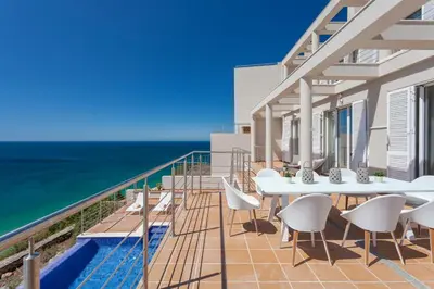 a balcony with a table and chairs and the ocean at Villa Mar a Vista in Salema