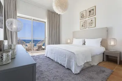 a white bedroom with a bed and a large window at Villa Mar a Vista in Salema