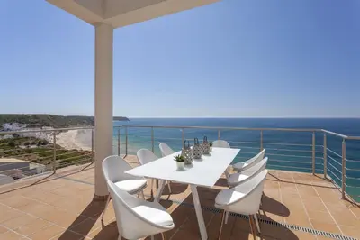 a white table and chairs on a balcony with the ocean at Villa Mar a Vista in Salema