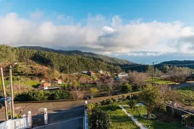 a bedroom with a white bed and a wooden floor at Cantinho do Céu, Views, Peace, Comfort & BBQ in Ribeira Brava