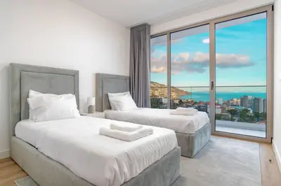 two beds in a room with a large window at The Place Funchal View in Funchal