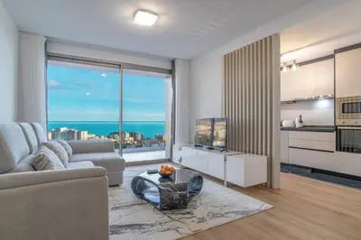a living room with a table and chairs and a kitchen at The Place Funchal View in Funchal