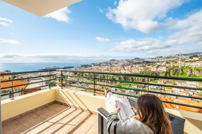 a woman sitting on a balcony reading a book at Villa Lucente by Homie in Santa Maria Maior