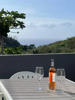 a bottle of whiskey and two wine glasses on a table at Casa Vereda do Calhau - With barbecue in Campanário