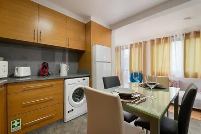 a kitchen with a dining table and a washing machine at Casa Vereda do Calhau - With barbecue in Campanário