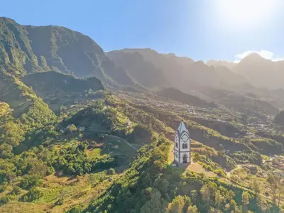 a clock tower in the middle of a valley with mountains at Casa Refúgio M in São Vicente