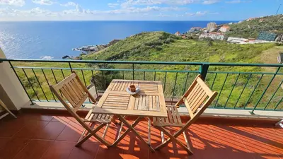 a table and chairs on a balcony with the ocean at Reis Magos View in Caniço