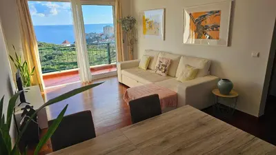 a living room with a couch and a large window at Reis Magos View in Caniço
