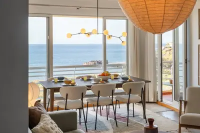 a dining room with a table and chairs and the ocean at Apartamento Paz e Sossego - By Wehost in Panasqueira