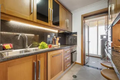 a kitchen with wooden cabinets and bar stools at Apartamento Paz e Sossego - By Wehost in Panasqueira