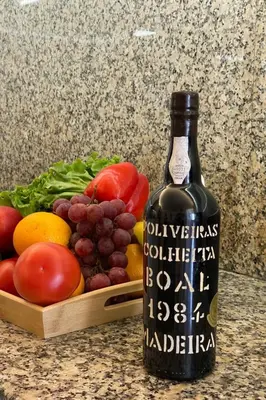 a bottle of wine next to a basket of fruits and vegetables at Holiday Home Ideales Familienhaus mit freiem Stadt- und Meerblick by Interhome in Funchal