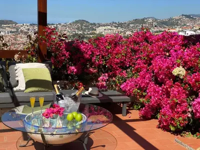 a patio with pink flowers and a glass table at Holiday Home Ideales Familienhaus mit freiem Stadt- und Meerblick by Interhome in Funchal