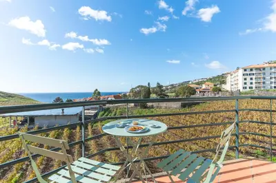 a table and chairs on a balcony with the ocean at Sunrising Apartment by Atlantic Holiday in Caniço