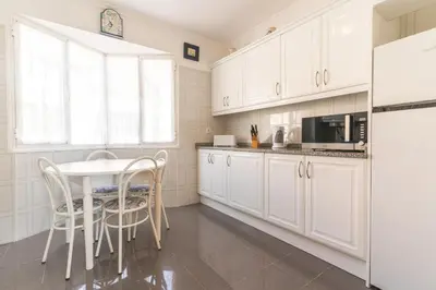 a kitchen with white cabinets and a table and chairs at Sunrising Apartment by Atlantic Holiday in Caniço