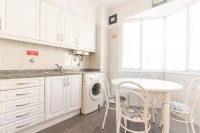 a white kitchen with a washing machine and a table at Sunrising Apartment by Atlantic Holiday in Caniço
