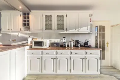 a white kitchen with white cabinets and a microwave at Melody House of Ponta do Sol in Canhas
