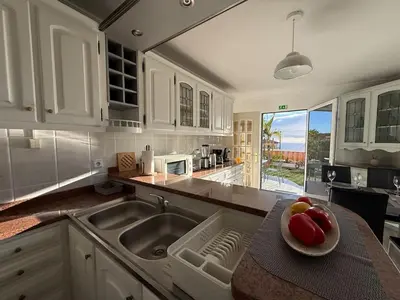 a kitchen with a sink and a plate of fruit on a counter at Melody House of Ponta do Sol in Canhas