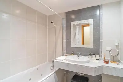 a white bathroom with a sink and a bath tub at Vista Calheta Apartment in Calheta