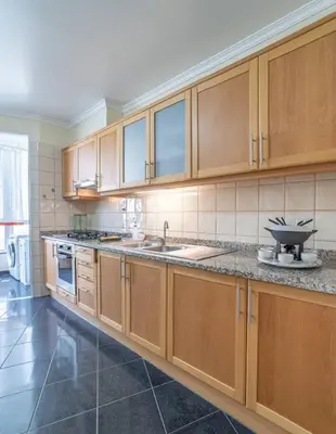 a large kitchen with wooden cabinets and a sink at Vista Calheta Apartment in Calheta