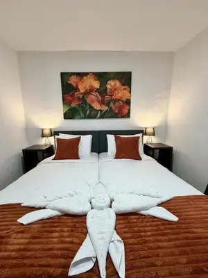 a bedroom with a large bed with white sheets and orange pillows at Ocean View Guest House in São Vicente