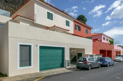 a building with green garage doors and parked cars at Garajau Lovers Retreat House 3BR by Wanderlust Madeira in Caniço