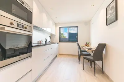 a kitchen with white cabinets and a table and chairs at Breeze House 2 by AH in Caniço