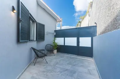 a patio with a black door and a chair at Breeze House 2 by AH in Caniço